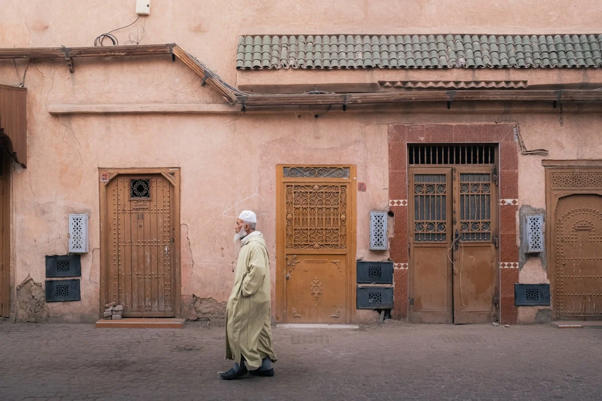 Man in traditional clothing walks past buildings