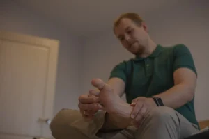 Adult man examines his own foot. Orthopedic problems concept.